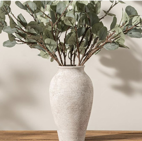 Large neutral ceramic vase with eucalyptus stems styled on a wooden surface for organic modern home décor.