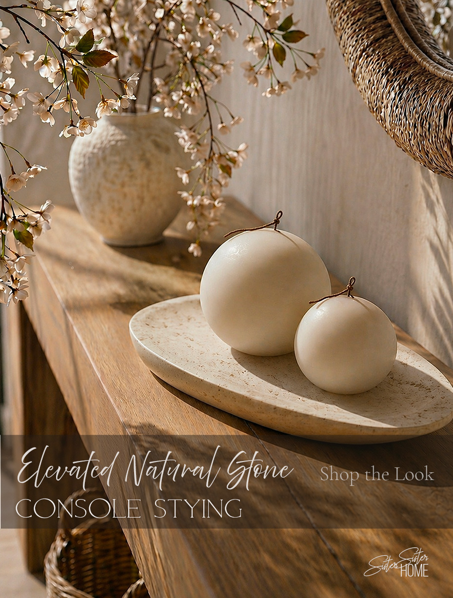 Elevated organic modern console styling featuring a natural travertine tray, neutral sphere candles, soft cherry blossom branches, and warm wood textures.