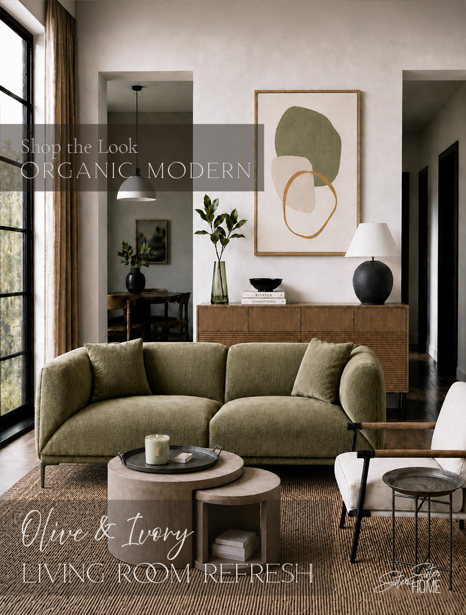 Organic modern living room with olive green sofa, ivory accent chair, round nesting coffee tables, fluted wood sideboard, abstract wall art, and warm neutral styling.