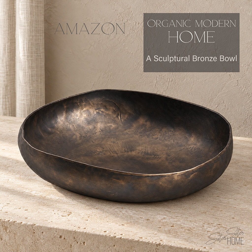 Bronze-finish sculptural aluminum bowl styled on a light stone console in an organic modern home.